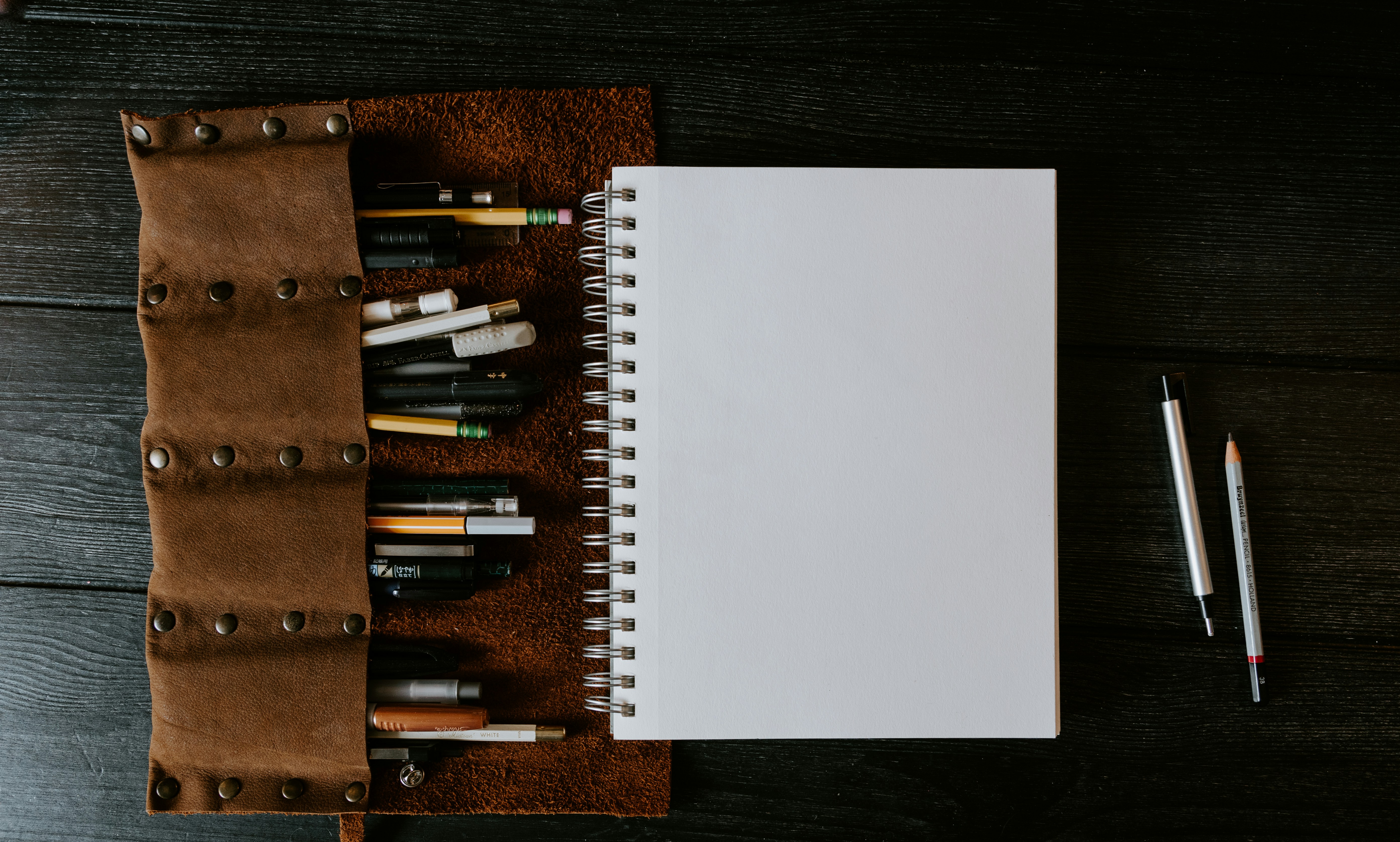 a flat layout of blank notebook, pencils, eraser and pens